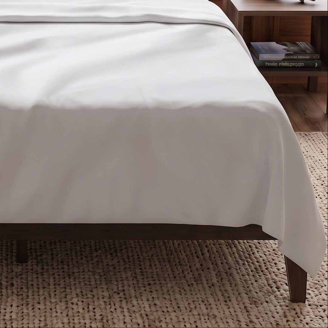 A neatly made bed with white bedding and two white pillows, set in a rustic bedroom with a dark upholstered headboard. Large windows behind the bed offer a scenic view of a forested coastline and ocean waves.